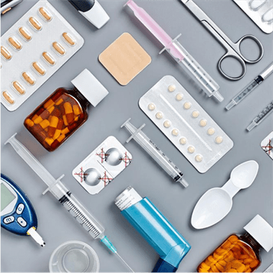 A flat lay image of various medical supplies and medications, including pills, syringes, an inhaler, a blood glucose meter, a bottle of capsules, a bandage, scissors, and a spoon.