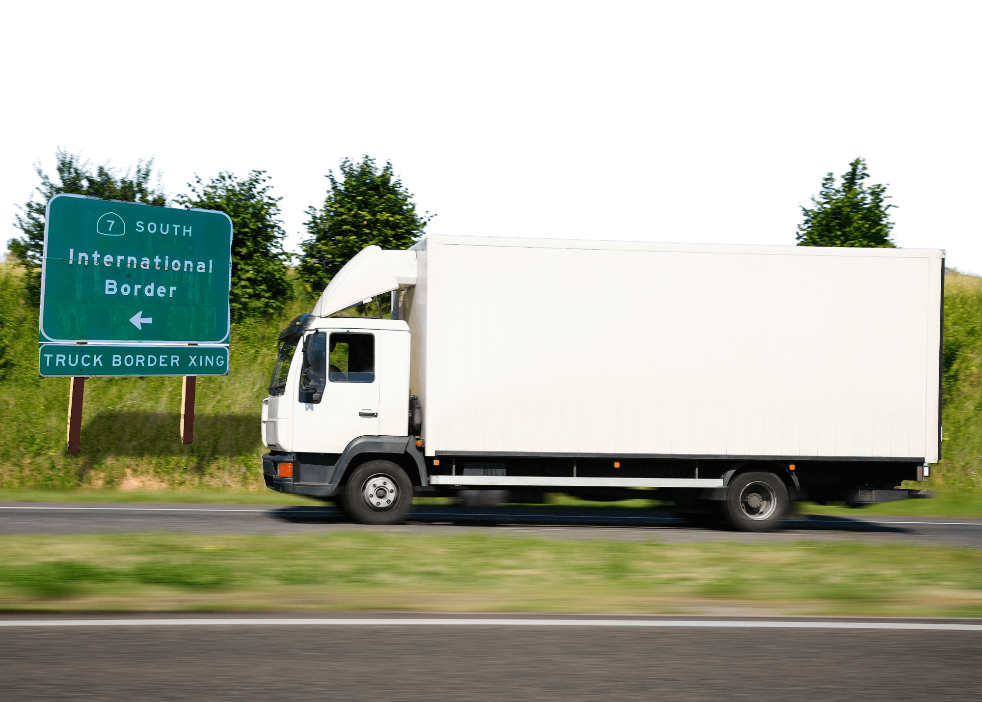 A large white truck on a highway with a sign in the background reading 