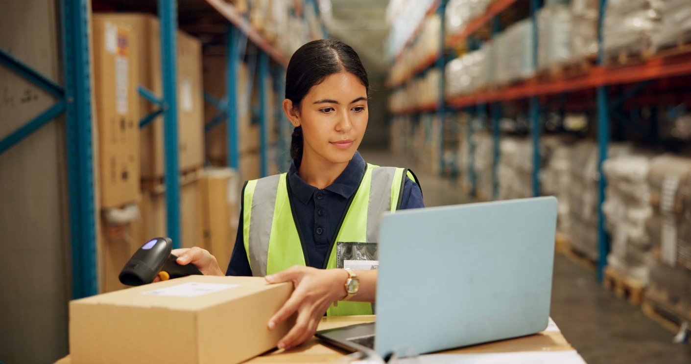 Warehouse worker scanning package and tracking expedited freight using logistics software.